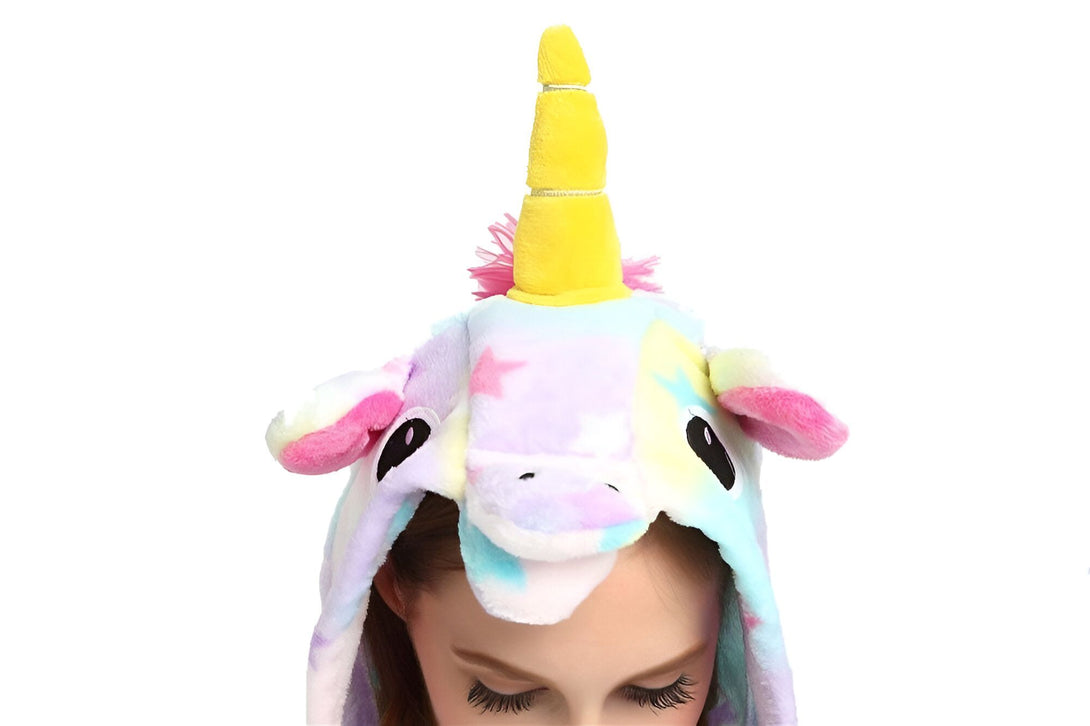 Une combinaison pyjama licorne avec une capuche. La combinaison est rose et bleue avec des étoiles et la capuche a une corne et des oreilles de licorne.