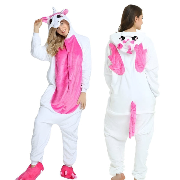 Une femme porte une combinaison pyjama licorne rose et blanche. La combinaison est à capuche et a des ailes et une queue de licorne. La femme est debout et regarde l'appareil photo.