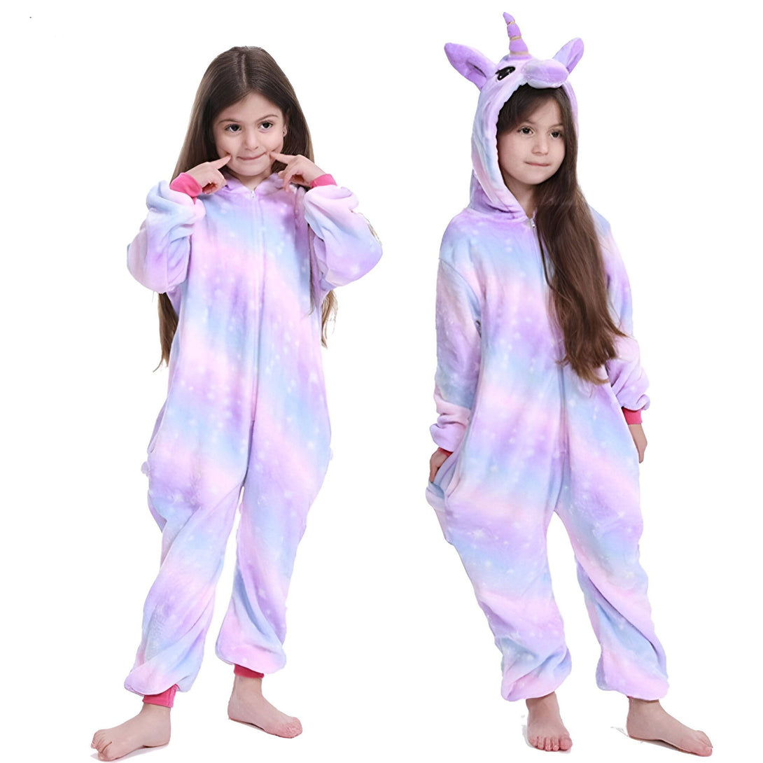 Deux jeunes filles portent des pyjamas licorne. Les pyjamas sont roses et violets avec une capuche en forme de tête de licorne.