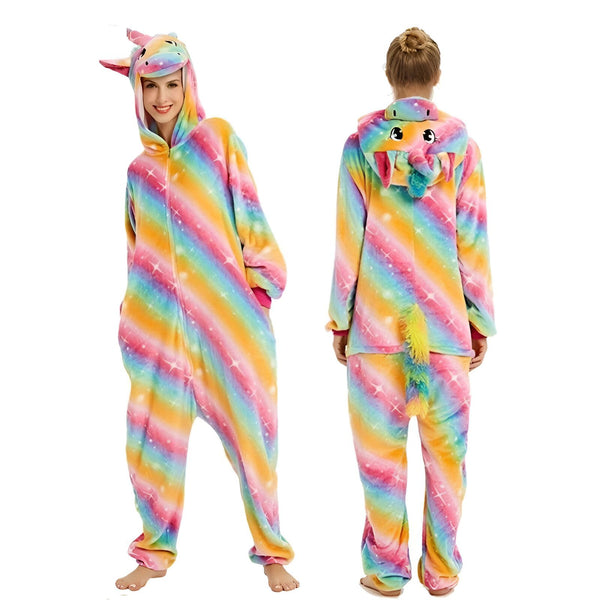 Une femme porte une combinaison pyjama licorne arc-en-ciel avec une capuche et une queue de cheval. La combinaison est rose, jaune, verte, bleue et violette avec des étoiles blanches.