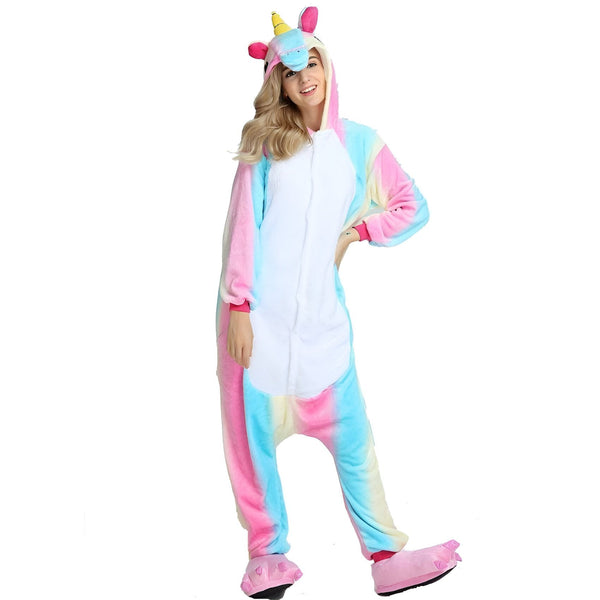 Une femme porte un pyjama licorne. Le pyjama est rose, bleu et blanc. Il a une capuche avec une corne de licorne. La femme est heureuse et sourit.