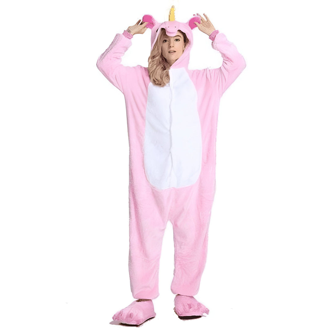 Une jeune femme porte une combinaison pyjama licorne rose et blanche. Elle a les mains sur la tête et sourit.