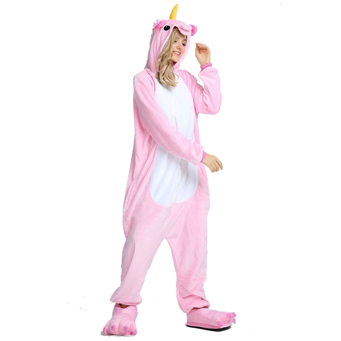 Une femme porte un pyjama licorne rose avec une capuche et des pieds en forme de pattes de licorne.