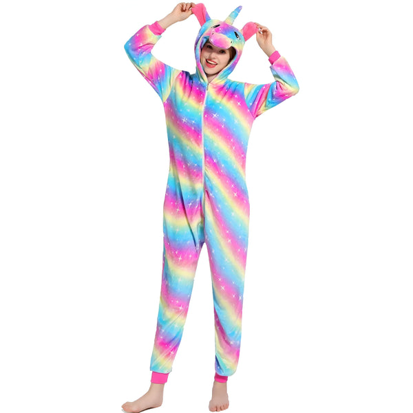 Une femme souriante portant un pyjama combinaison licorne arc-en-ciel. Le costume est doux, coloré et a une capuche avec une corne et des oreilles. Elle lève les bras. Idéal pour se détendre à la maison ou pour une fête costumée., 45502011539711,45502011638015,45502011670783,45502011703551,45502011736319,45502011769087,45502011834623,45502011965695 | Licorne Shop