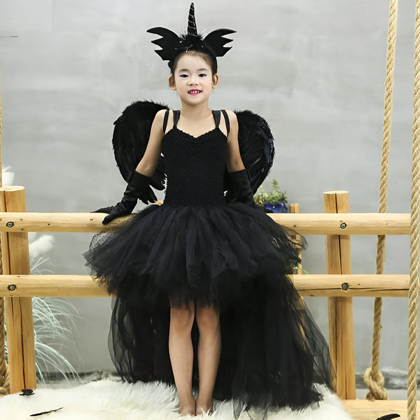 Fillette souriante en costume de licorne noire avec ailes et tutu. Déguisement d'Halloween ou de fête. Bandeau licorne sur la tête, gants noirs. Enfant déguisé pour un événement spécial., 45501281730815,45501281763583,45501281796351,45501281829119,45501281861887,45501281927423,45501281960191,45501281992959 | Licorne Shop