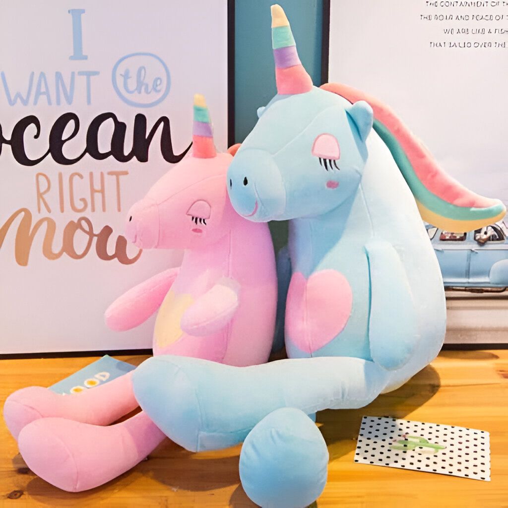 Deux licornes en peluche colorées, rose et bleu clair, avec des détails brodés, assises sur une surface en bois. Un poster avec le texte "I want the ocean right now" est visible en arrière-plan., 45501068312831 | Licorne Shop