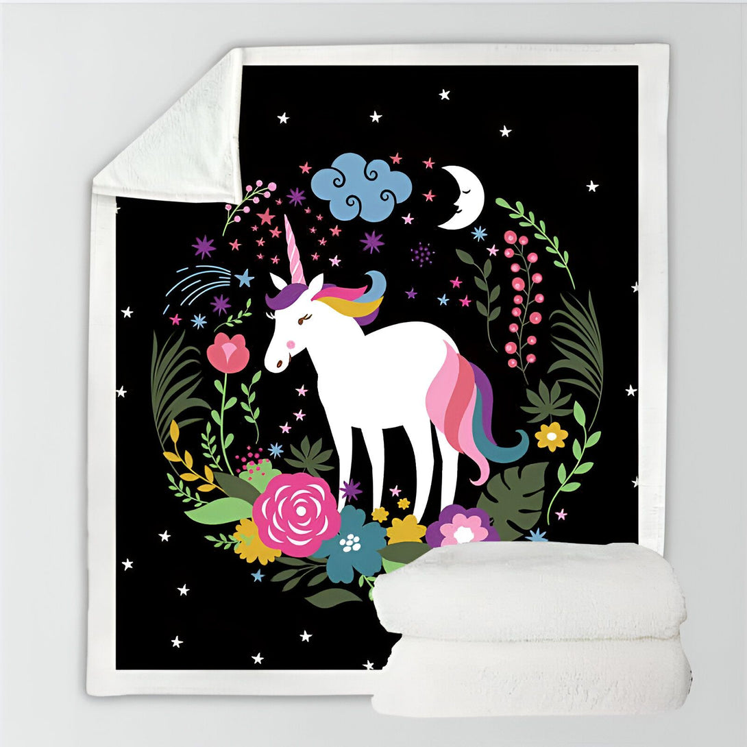 Couverture noire avec motif de licorne blanche, crinière multicolore, entourée de fleurs, d'étoiles, d'une lune et d'un nuage. Deux couvertures blanches sont pliées en bas., 45501034299647 | Licorne Shop