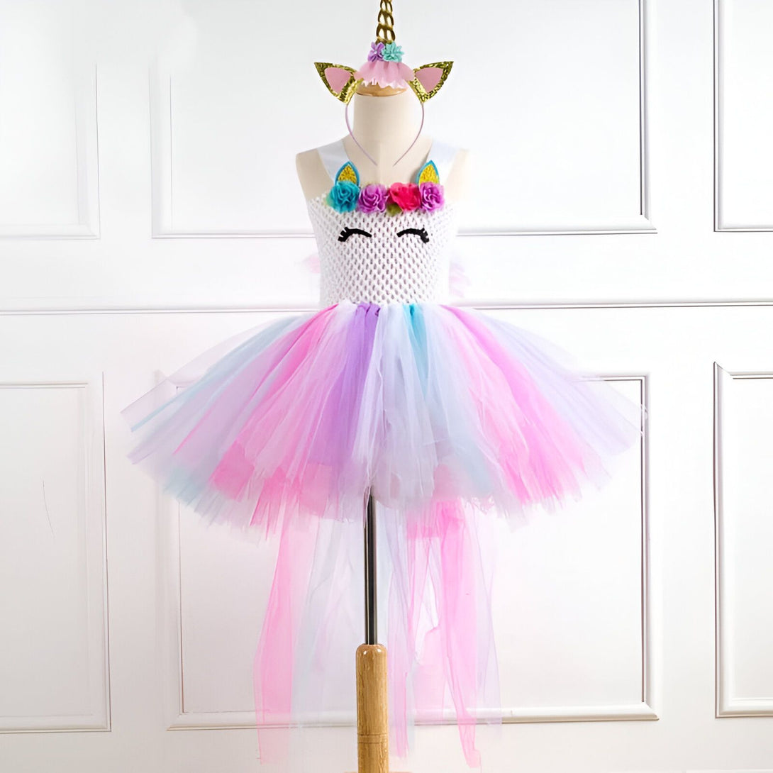 Costume de licorne pour enfant sur un mannequin. Robe avec corsage blanc et tutu multicolore rose, violet et bleu. Un serre-tête licorne doré complète la tenue. Parfait pour une fête costumée ou Halloween., 45501285236991,45501285269759,45501285302527,45501285335295,45501285368063,45501285400831,45501285433599,45501285466367 | Licorne Shop