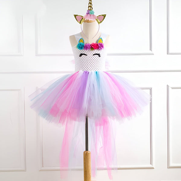 Costume de licorne pour enfant sur un mannequin. Robe avec corsage blanc et tutu multicolore rose, violet et bleu. Un serre-tête licorne doré complète la tenue. Parfait pour une fête costumée ou Halloween., 45501285236991,45501285269759,45501285302527,45501285335295,45501285368063,45501285400831,45501285433599,45501285466367 | Licorne Shop
