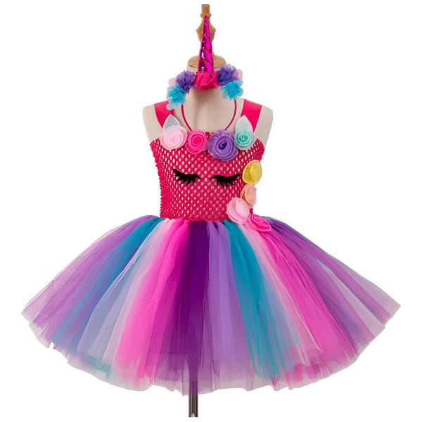 Robe de licorne pour enfant sur un mannequin, avec un corsage rose orné de fleurs et de cils endormis, une jupe tutu multicolore (rose, violet, turquoise), et un serre-tête assorti avec une corne. Costume de déguisement., 45501274620159,45501274652927,45501274685695,45501274718463,45501274783999,45501274947839,45501275013375,45501275046143 | Licorne Shop