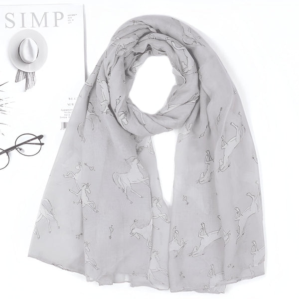 Écharpe gris clair avec motifs de cavaliers et de chevaux. Sur le côté, on aperçoit un magazine, un chapeau blanc et des lunettes rondes., 45502081433855 | Licorne Shop
