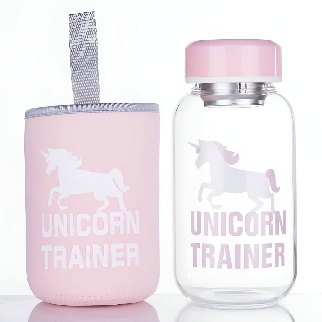 Gourde et son étui rose pastel décorés avec un motif de licorne et l'inscription "Unicorn Trainer". La gourde est en verre transparent avec un bouchon rose., 45501176742143 | Licorne Shop