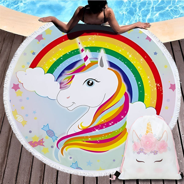 Serviette de plage ronde avec motif licorne arc-en-ciel et son sac de rangement assorti. Une femme se détend au bord de la piscine, sa serviette licorne à ses côtés. Accessoire de bain original et fun pour l'été., 45501226746111 | Licorne Shop