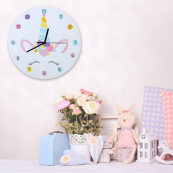 Horloge murale pour enfant avec motif licorne, posée dans une chambre d'enfant décorée avec des fleurs, un lapin en peluche et des coussins. Décoration de chambre de bébé., 45501135683839 | Licorne Shop