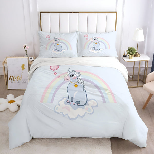 Une chambre avec une parure de lit licorne. La parure de lit est composée d'une housse de couette et de deux taies d'oreiller. La housse de couette est imprimée d'une licorne assise sur un nuage. La licorne est entourée d'un arc-en-ciel et de bulles. Les taies d'oreiller sont imprimées de la même licorne. La parure de lit est en coton et est lavable en machine.