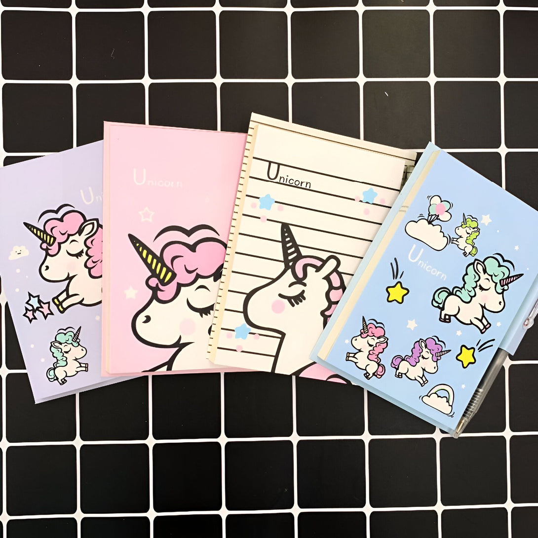 Quatre petits carnets avec des couvertures à motifs licorne de différentes couleurs (violet, rose, beige et bleu) sont disposés sur un fond à carreaux noirs et blancs. Un stylo est visible à côté du carnet bleu., 45501153083647 | Licorne Shop
