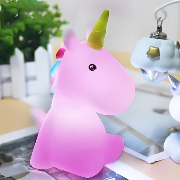 Lampe de chevet rose en forme de licorne, avec une corne jaune, posée sur une table. Une autre lampe en forme de nuage est visible en arrière-plan., 45501072081151 | Licorne Shop