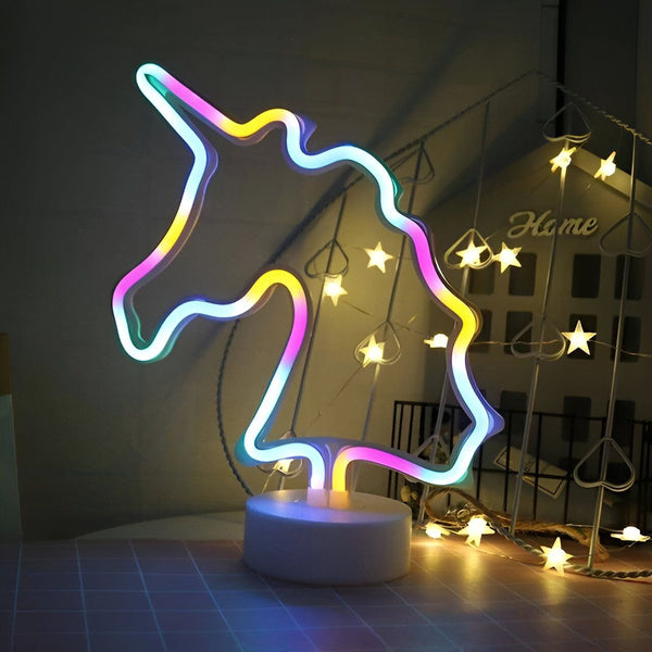 Une enseigne lumineuse en forme de licorne est posée sur une table. La licorne est multicolore et est éclairée.