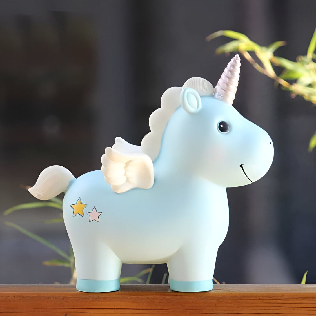 Tirelire en forme de licorne bleu pastel avec des ailes et une corne blanche. Des étoiles dorées et roses décorent le côté. Parfait pour apprendre aux enfants à économiser. Décoration mignonne et ludique pour une chambre d'enfant., 45501161931007 | Licorne Shop