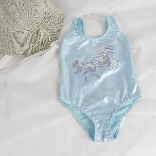 Maillot de bain bleu scintillant pour enfant avec motif licorne pailletée, présenté à côté d'un chapeau de paille sur un tissu blanc. Vêtement de plage d'été pour filles., 45501116547327 | Licorne Shop
