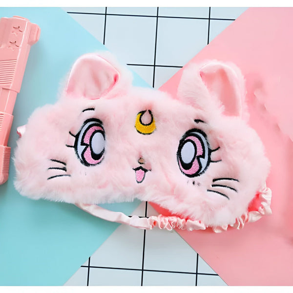 Masque de sommeil rose en forme de chat avec des broderies détaillées, des oreilles pointues et un élastique froncé. À côté, un pistolet jouet rose sur fond divisé bleu et rose avec motif quadrillé. Accessoire de repos fantaisiste., 45501050913023 | Licorne Shop