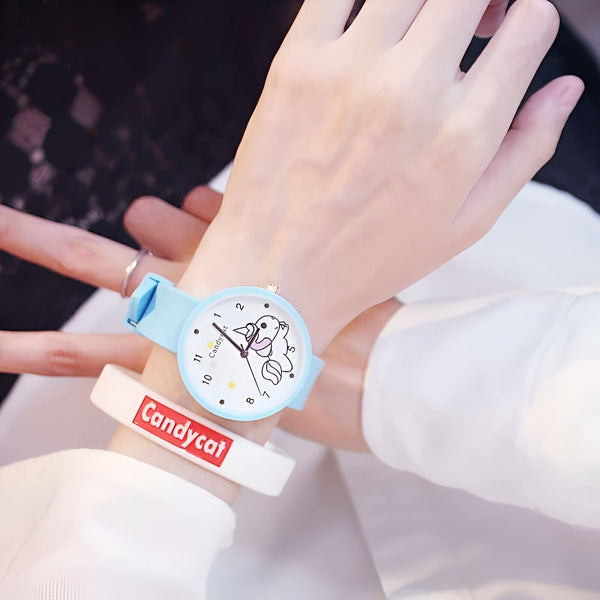 Gros plan sur le poignet d'une personne portant une montre-bracelet bleu clair avec un cadran blanc orné d'un dessin de licorne et un bracelet "Candycat" blanc et rouge., 45501128835327 | Licorne Shop