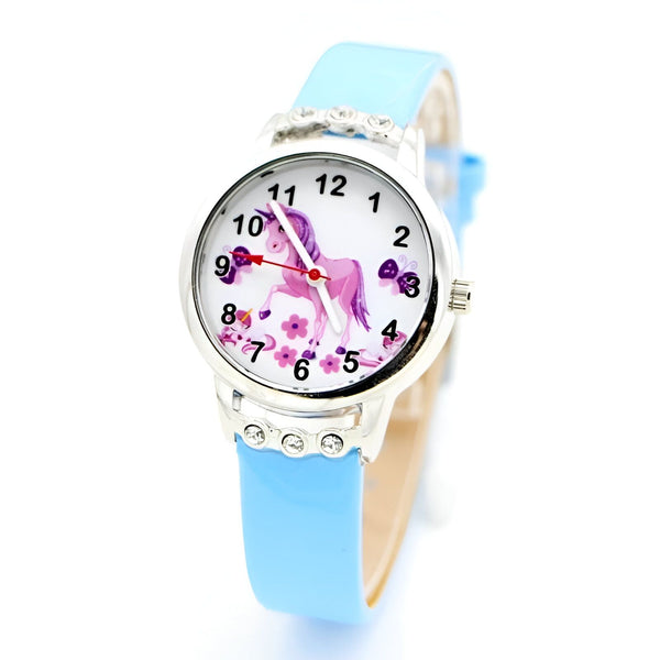 Une montre licorne avec un bracelet en cuir bleu. Le cadran de la montre est blanc avec une image de licorne et des fleurs.