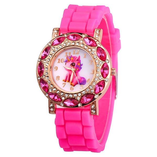 Une montre rose avec un bracelet en silicone et un cadran rond avec une image de licorne. La montre est décorée de strass roses et dorés.