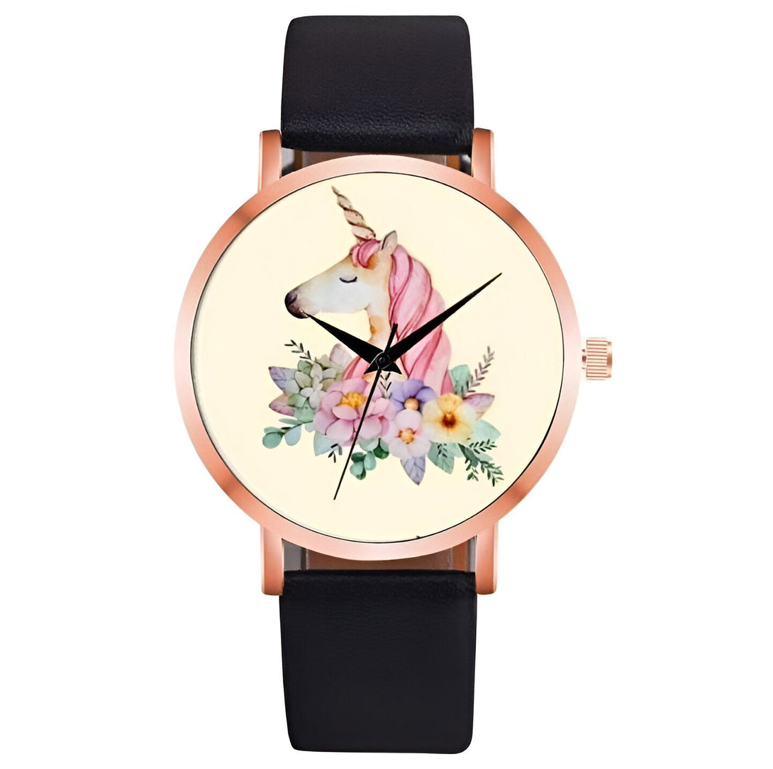 Une montre analogique à quartz avec un bracelet en cuir noir et un cadran rond en métal doré. Le cadran représente une licorne blanche avec une crinière et une queue roses, entourée de fleurs et de feuillage.