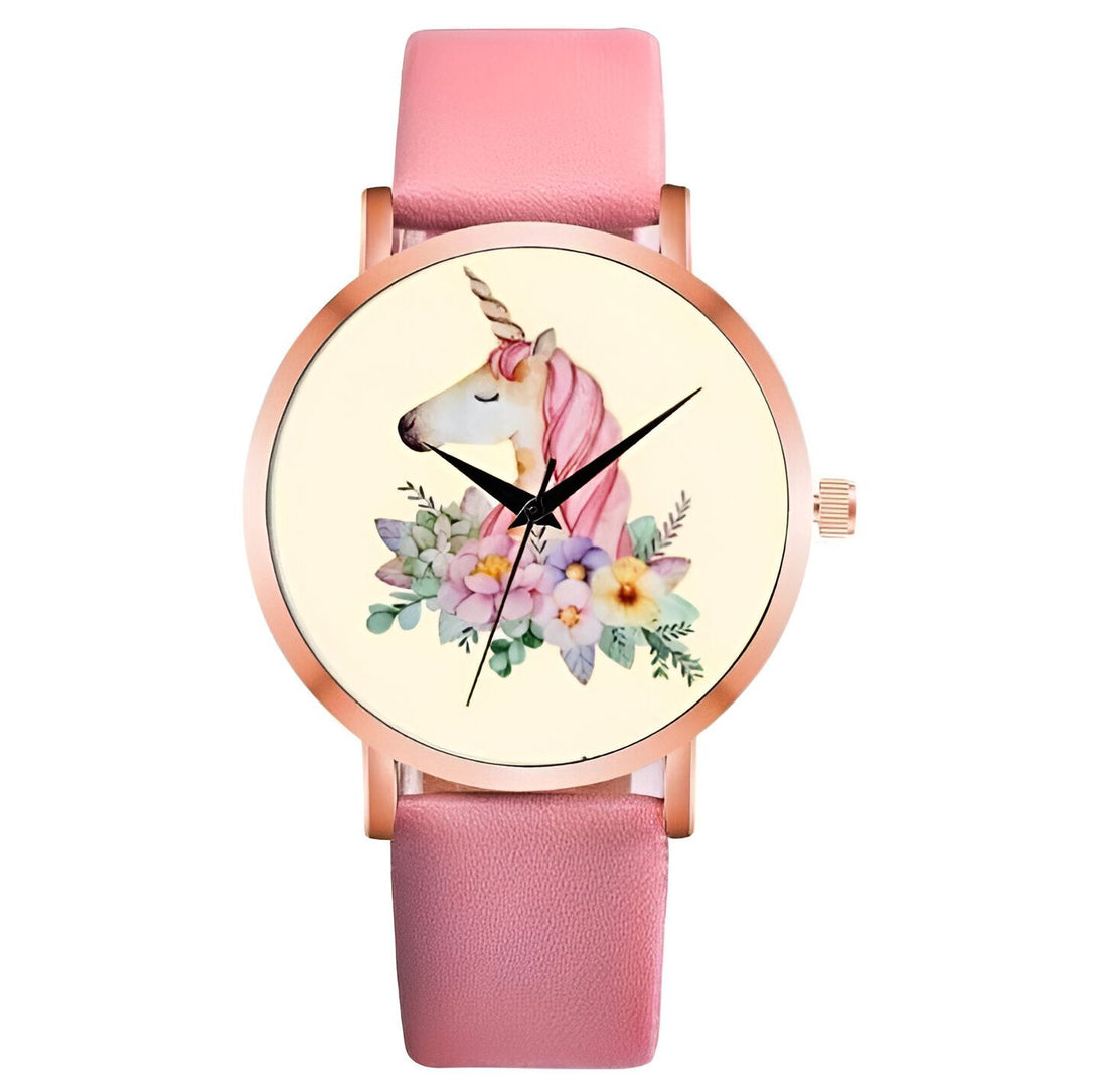 Une montre rose avec un cadran rond et un bracelet en cuir rose. Le cadran de la montre est décoré d'une illustration d'une licorne blanche avec une crinière et une queue roses, entourée de fleurs colorées.