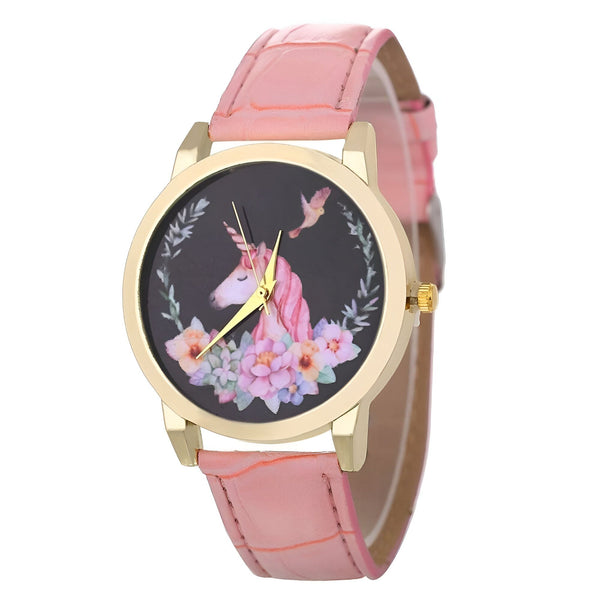 Une montre licorne avec un bracelet en cuir rose. Le cadran de la montre est noir avec une image de licorne blanche et de fleurs roses.