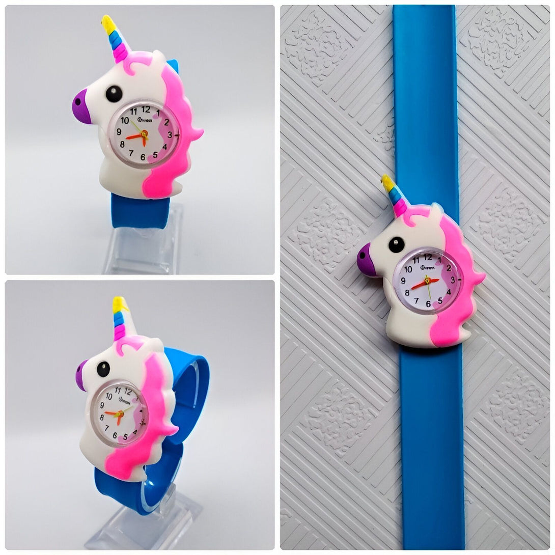 Une montre en forme de licorne blanche et rose avec un bracelet en silicone bleu. La montre a un cadran analogique avec des chiffres arabes et des aiguilles roses. La licorne a une crinière et une queue arc-en-ciel.