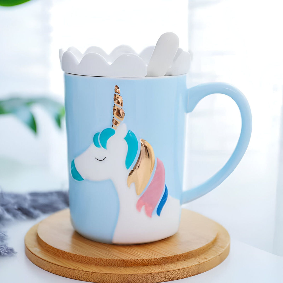 Image d'un joli mug bleu clair décoré d'un dessin de licorne blanche avec crinière colorée et corne dorée. Le mug repose sur un sous-tasse en bois et a un couvercle blanc avec une cuillère assortie., 45501196108031 | Licorne Shop