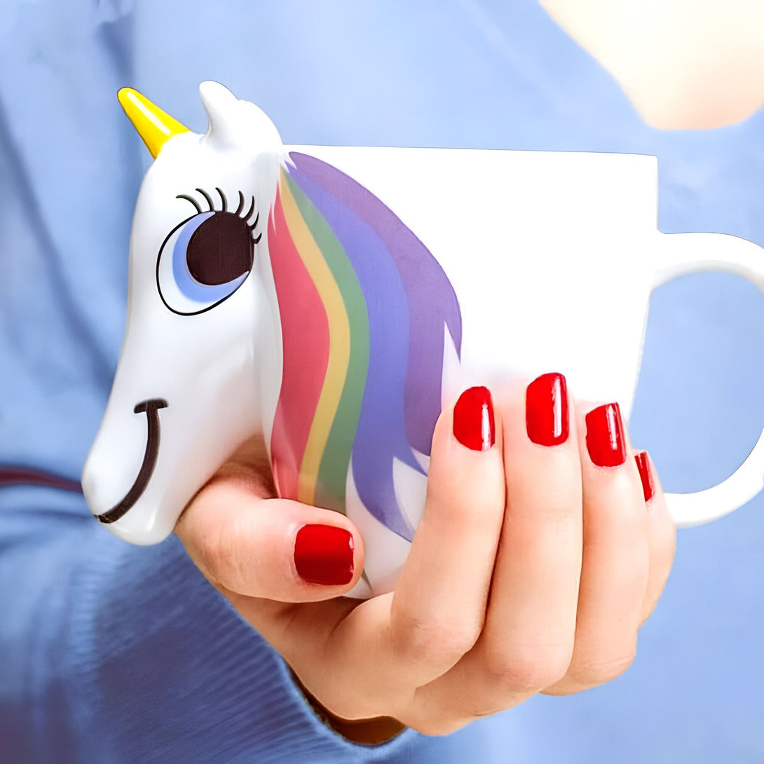 Personne tenant une tasse de café en forme de licorne blanche avec une crinière arc-en-ciel, des ongles rouges et un fond bleu., 45501188407551 | Licorne Shop