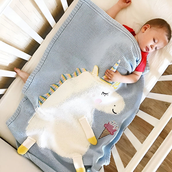 Un bébé dort dans un lit d'enfant, enroulé dans une couverture bleue avec une peluche licorne., 45501129326847,45501129359615,45501129392383,45501129425151,45501129457919,45501129490687,45501129523455,45501129556223,45501129588991,45501129621759,45501129654527,45501129687295,45501129720063 | Licorne Shop