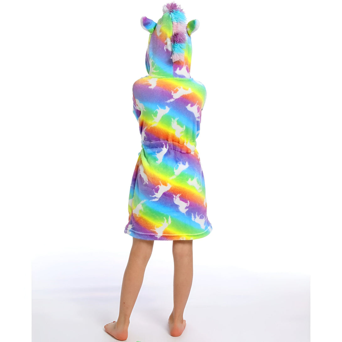 Une jeune fille porte une robe de chambre licorne arc-en-ciel à capuche. La robe de chambre est en peluche et a une ceinture à la taille. La capuche est bordée de fourrure blanche. La jeune fille est vue de dos.