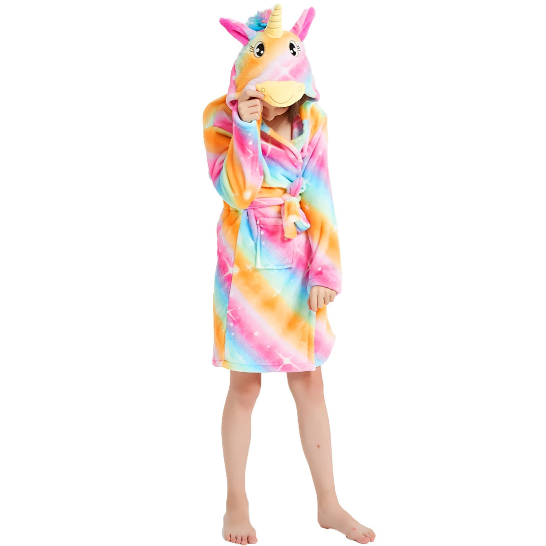 Une jeune fille porte une combinaison pyjama licorne arc-en-ciel avec une capuche.