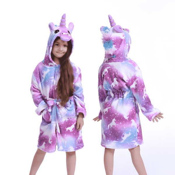 Fille portant un peignoir licorne doux. Devant, une fillette souriante pose en peignoir licorne, à capuche avec visage et corne. Dos, peignoir violet et bleu avec des motifs licornes. Le peignoir a une ceinture et des poches., 45502345806079,45502345838847,45502345871615,45502345904383,45502345937151,45502345969919,45502346002687,45502346035455 | Licorne Shop