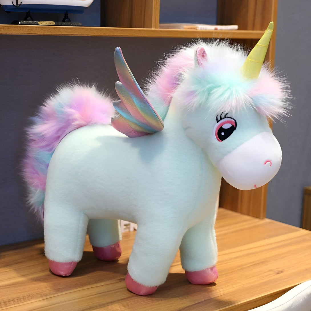 Une peluche licorne verte avec des ailes arc-en-ciel et une crinière et une queue multicolores.