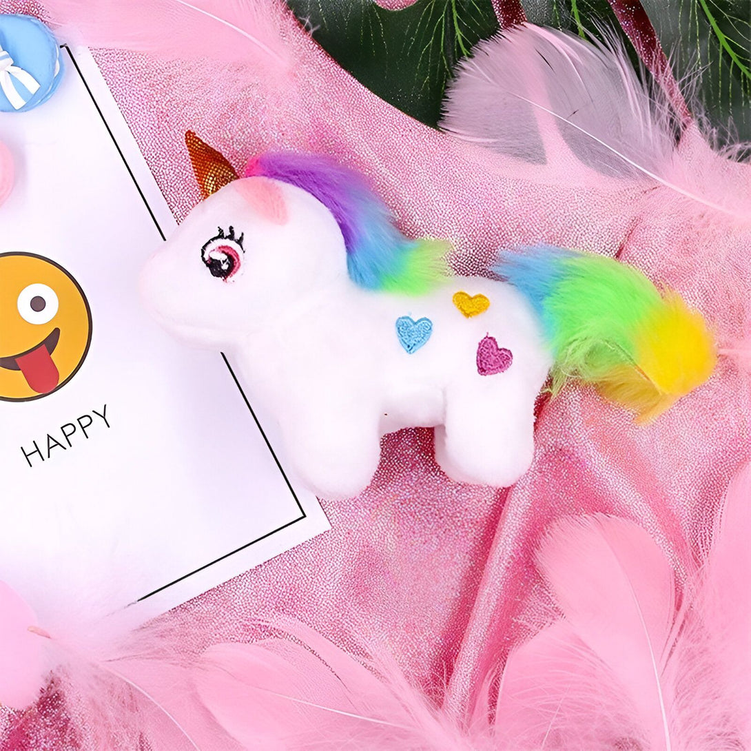 Une peluche licorne blanche avec une crinière arc-en-ciel et une queue arc-en-ciel avec des coeurs.