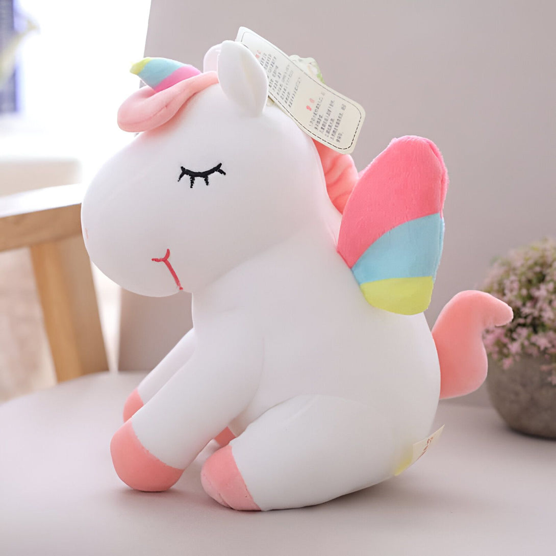 Peluche licorne blanche assise avec des ailes et une corne arc-en-ciel. Jouet doux pour enfants, décoration de chambre, cadeau d'anniversaire. Yeux brodés, détails roses et bleus., 45501420503295 | Licorne Shop