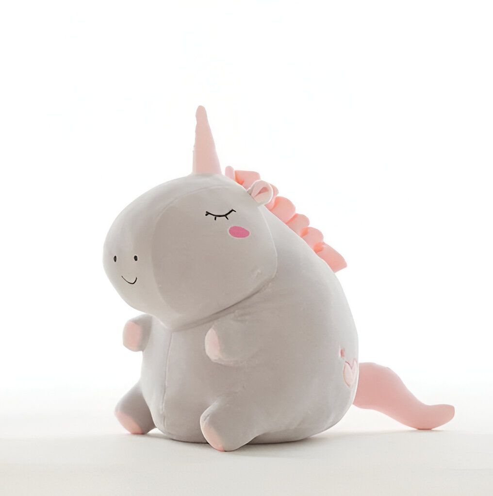 Une peluche licorne grise et rose avec une crinière et une queue rose. La peluche est assise et a les yeux fermés.