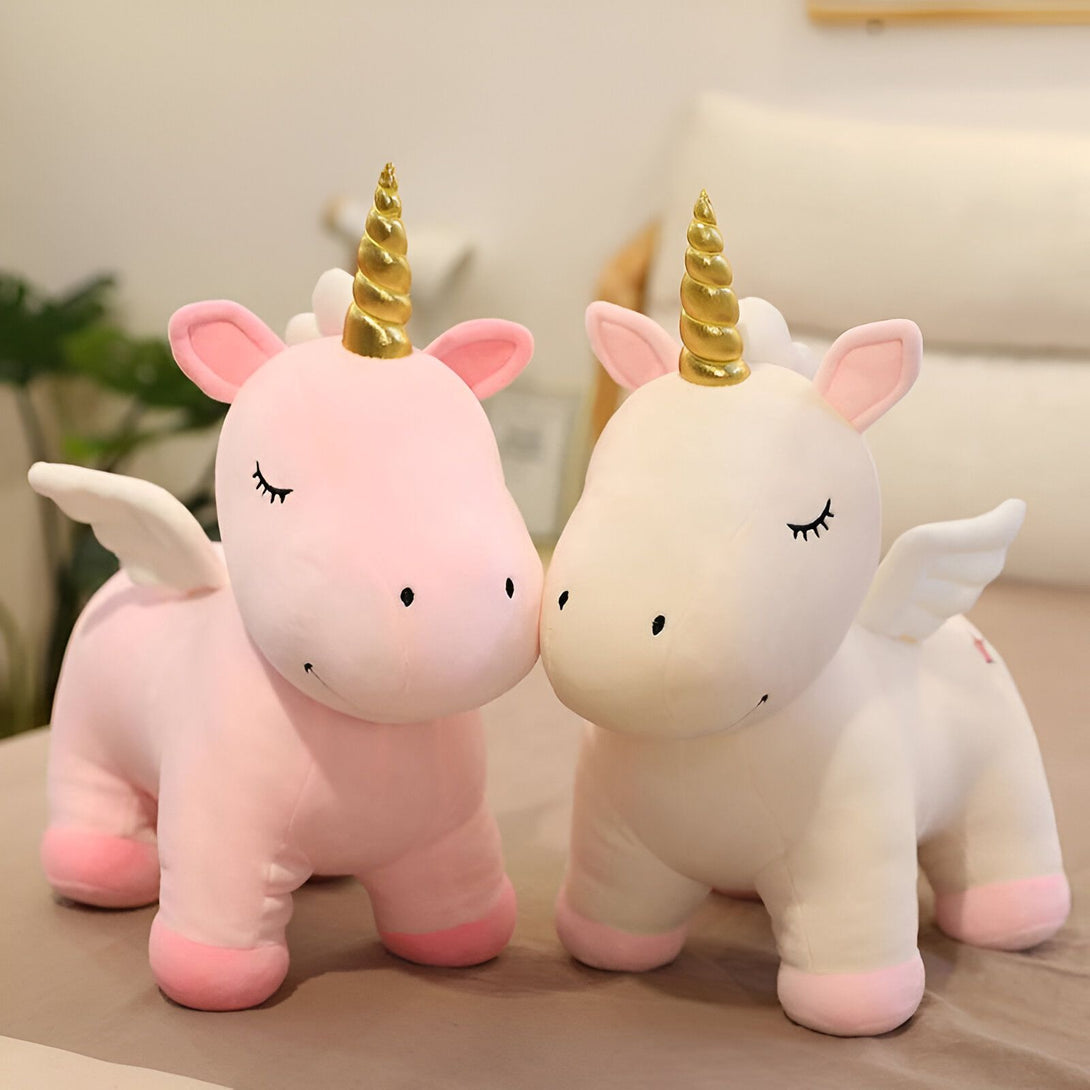 Deux peluches licornes blanches et roses avec des ailes et une corne dorée.