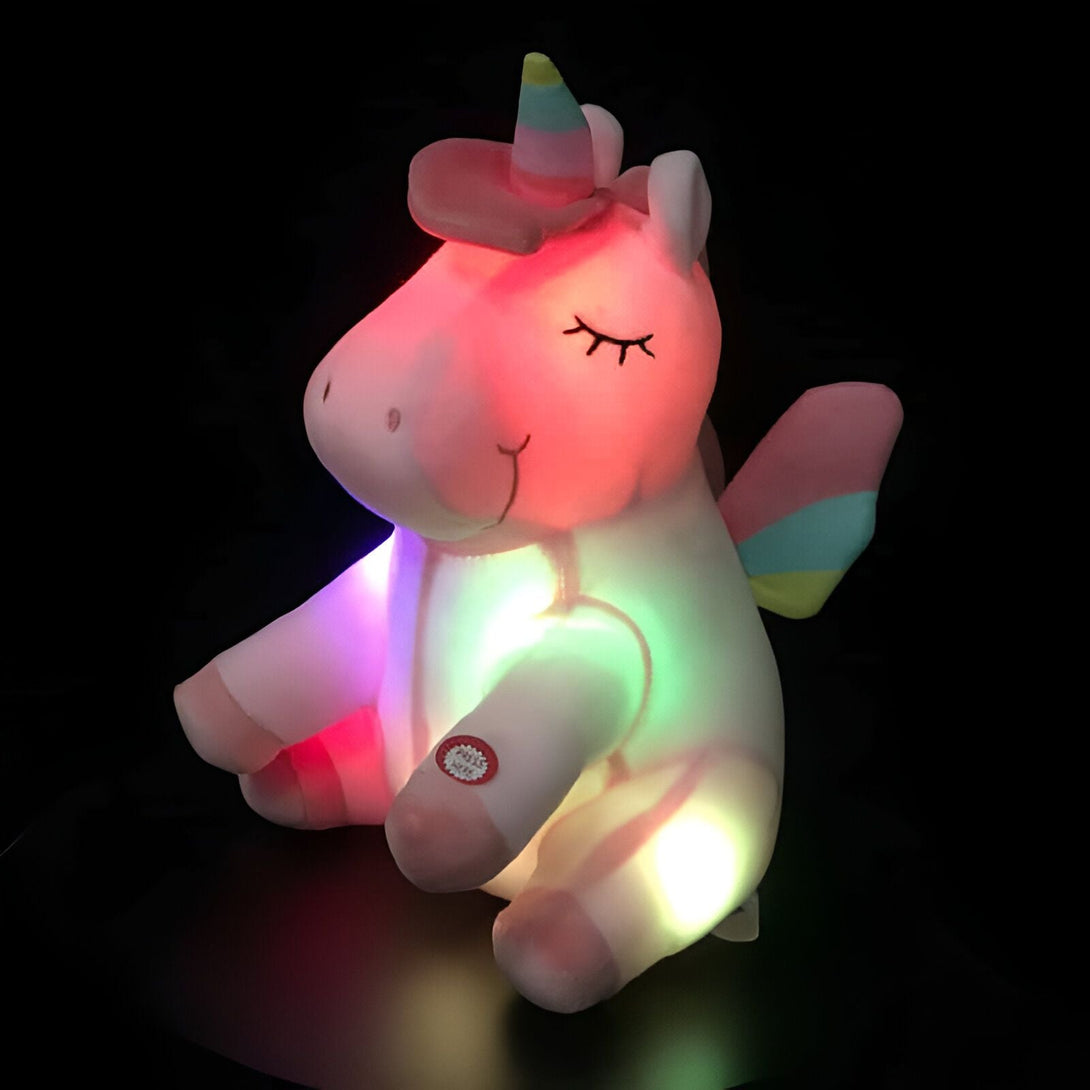 Peluche licorne lumineuse rose et blanche. Jouet doux avec ailes pastel et corne colorée, illuminé par des lumières LED multicolores. Idéal comme veilleuse pour enfants., 45501421224191 | Licorne Shop
