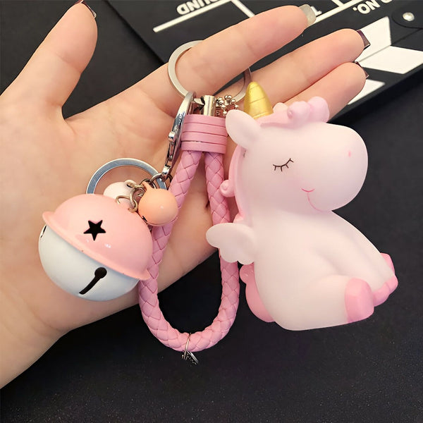 Gros plan d'une main tenant un porte-clés licorne rose avec un pompon et une clochette. Le porte-clés présente un design mignon et fantaisiste, idéal pour ajouter une touche d'originalité à vos clés ou votre sac. Accessoire tendance pour les fans de licornes., 45501158228223 | Licorne Shop