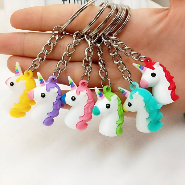 Porte-clés licorne colorés. Gros plan sur une main tenant plusieurs porte-clés en forme de têtes de licorne aux couleurs vives. Idéal pour les accessoires, la décoration ou les cadeaux pour enfants., 45501196763391 | Licorne Shop
