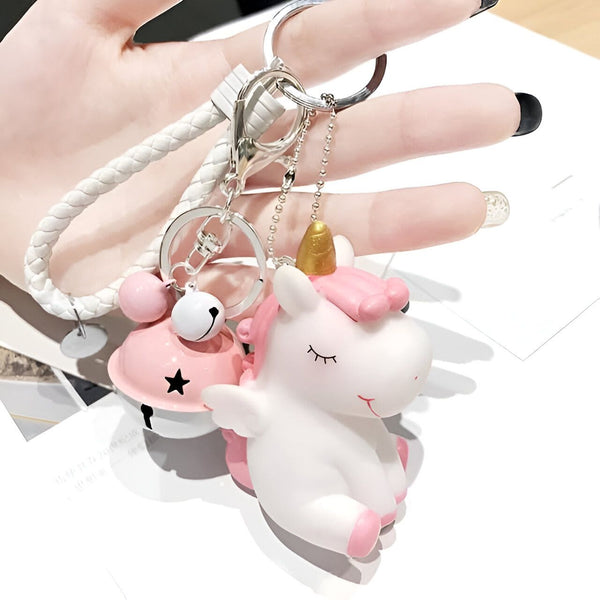 Un porte-clés fantaisie avec un licorne rose et blanche, une cloche rose et un cordon tressé blanc, tenu dans la main. Accessoire mignon et tendance., 45501197910271 | Licorne Shop