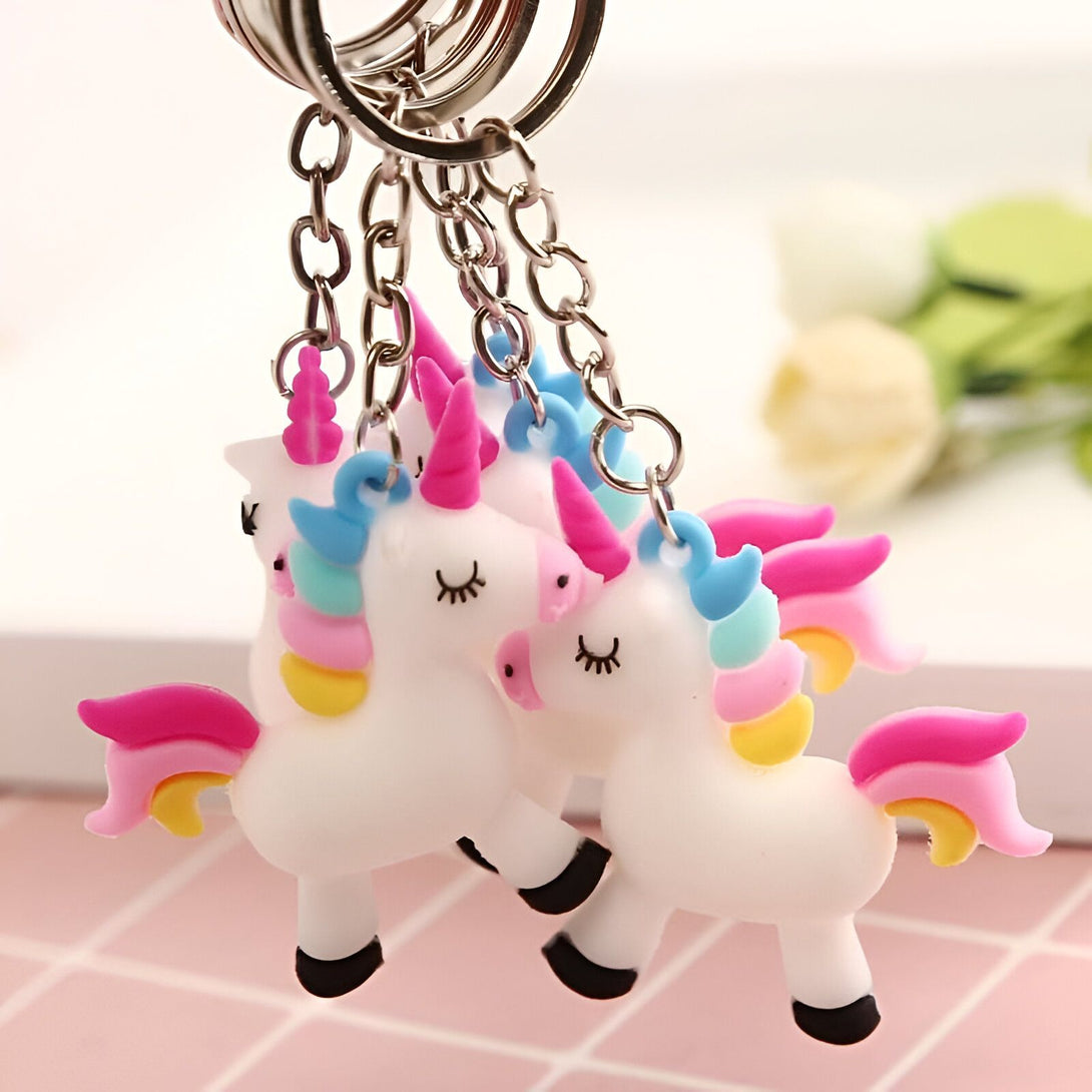 Plusieurs porte-clés licorne avec des corps blancs, des crinières et des queues colorées (rose, bleu, jaune) suspendus à des chaînes argentées. Les licornes ont des yeux fermés en forme de croissant., 45501160587519 | Licorne Shop