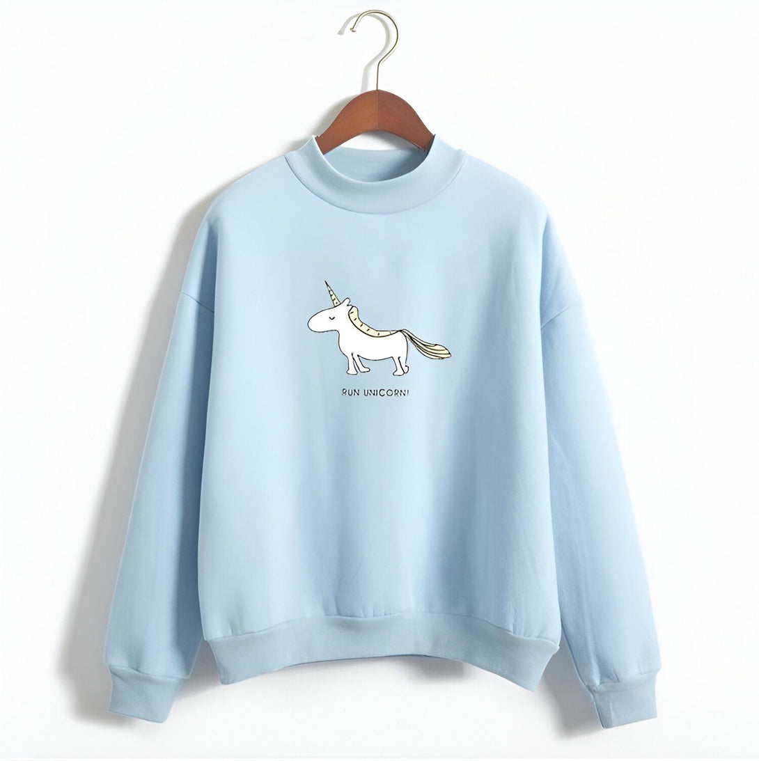 Le sweat-shirt bleu ciel a un col montant et des manches longues. Il est décoré d'une illustration d'une licorne blanche avec une crinière et une queue jaunes. La licorne est représentée en train de courir. Le texte "Run unicorn !" est écrit en dessous de la licorne.