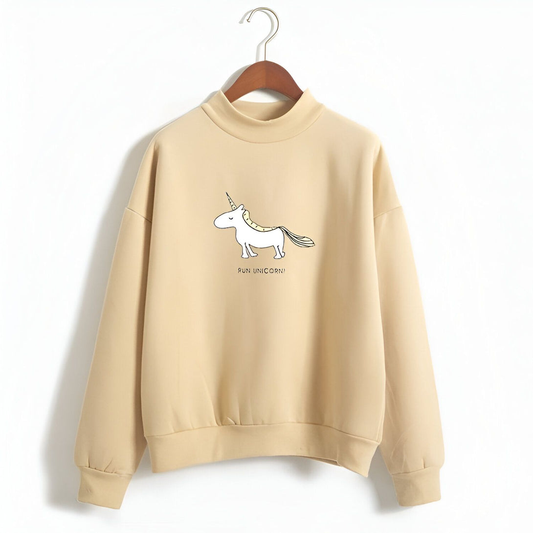 L'image représente un sweat-shirt beige avec un col montant. Il y a un dessin d'une licorne blanche avec une crinière et une queue jaunes. Le texte "Run unicorn !" est écrit en noir sous la licorne.